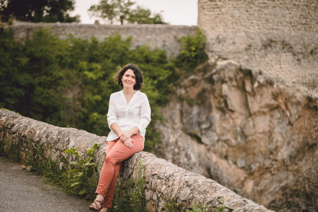 portrait corporate d'une jeune femme sur les hauteurs de tournon sur rhone elle est assise sur un muret en pierres