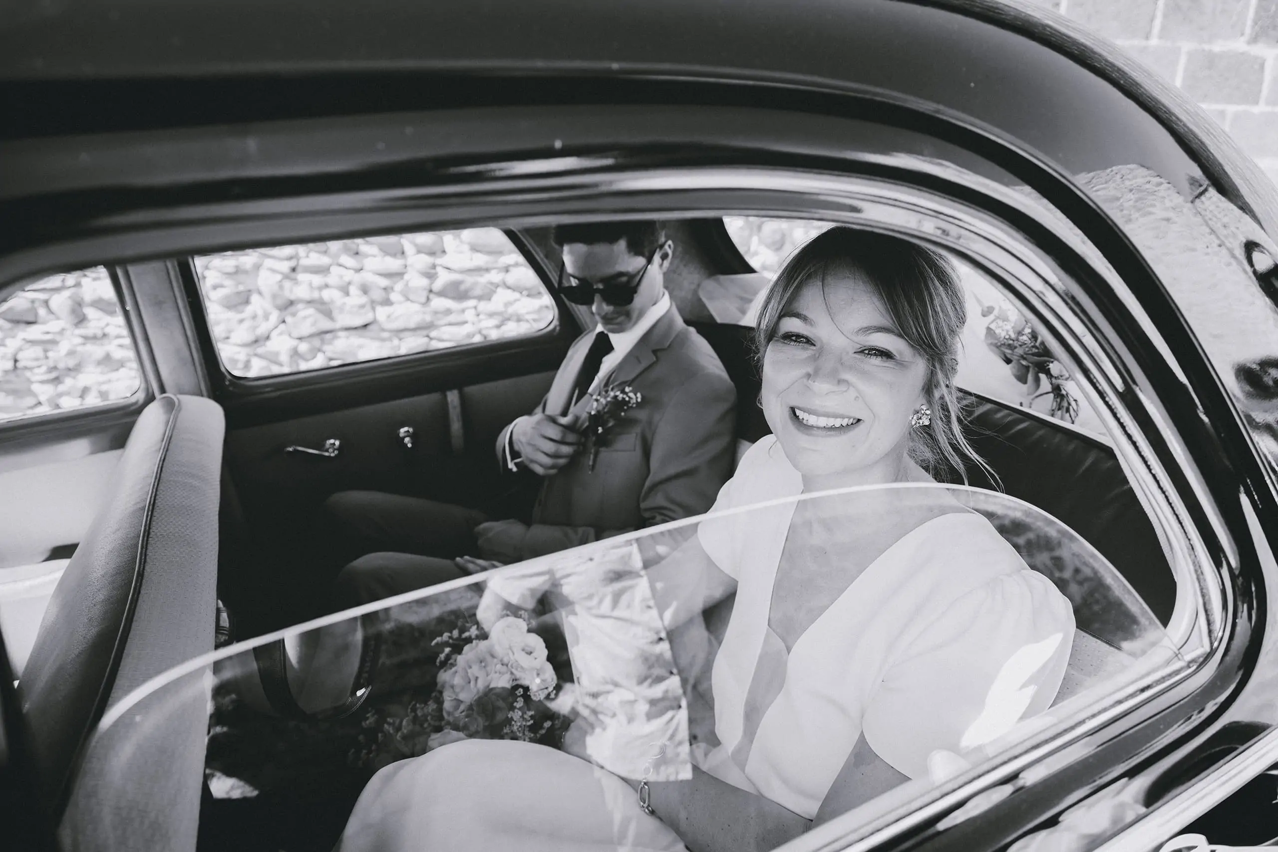 couple de mariés à travers la vitre leur voiture ancienne photo en noir et blanc