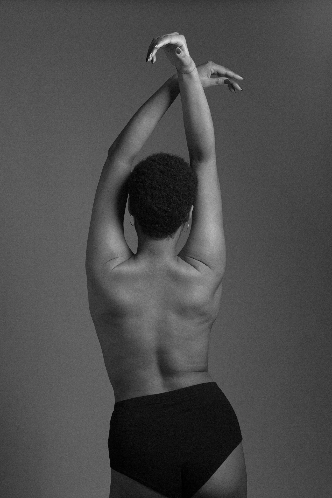 Photo d'une jeune femme métisse de dos en noir et blanc en studio photo