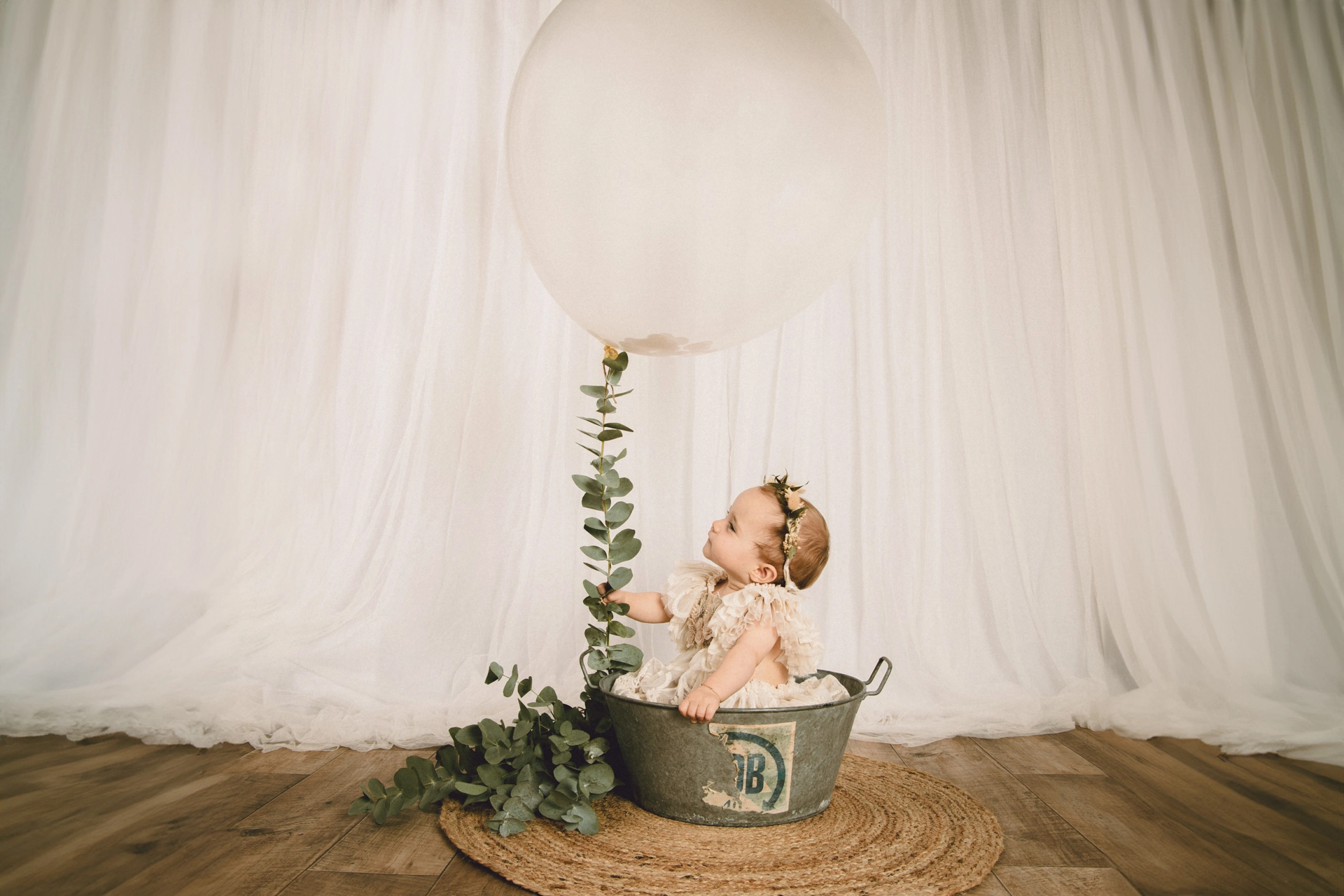petite fille en studio de photographie qui regarde un très gros ballon et de l'eucalyptus dans une bassine ancienne en inox