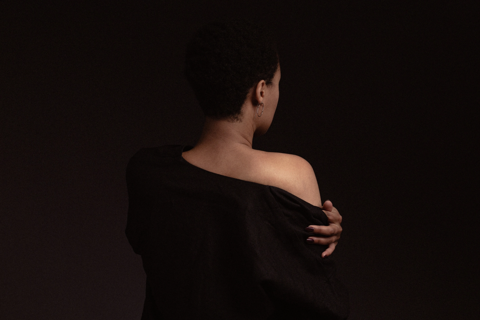 femme métisse de dos qui tient son haut sur son épaule