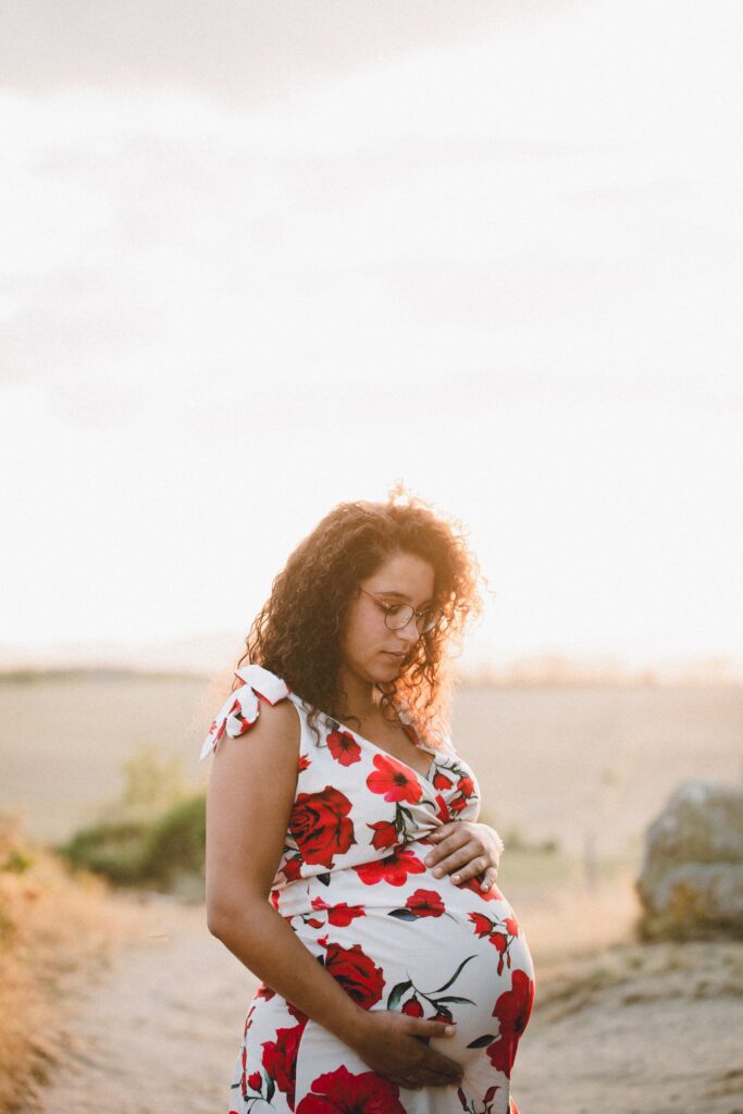 femme enceinte au coucher du soleil avec une robe a fleurs rouges