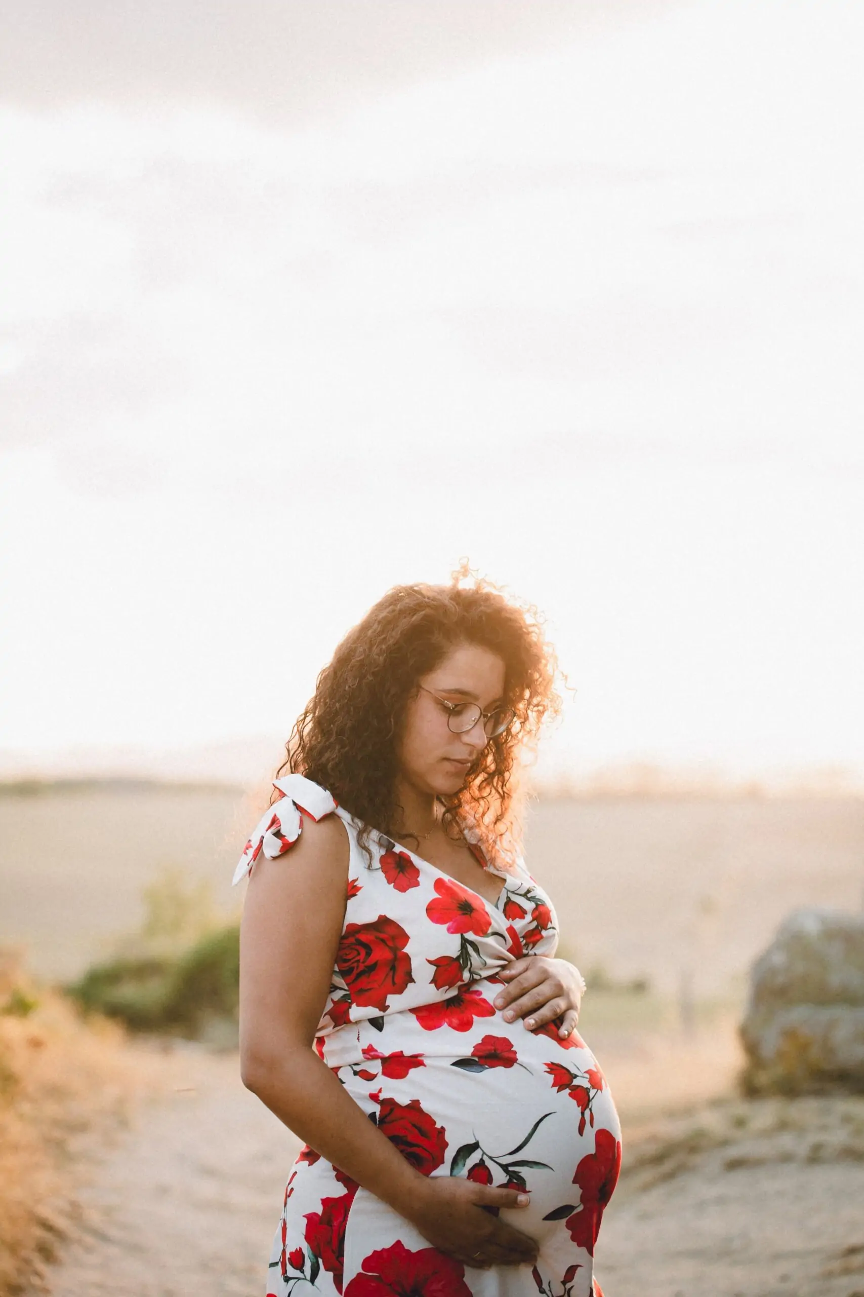 femme enceinte au coucher du soleil avec une robe a fleurs rouges