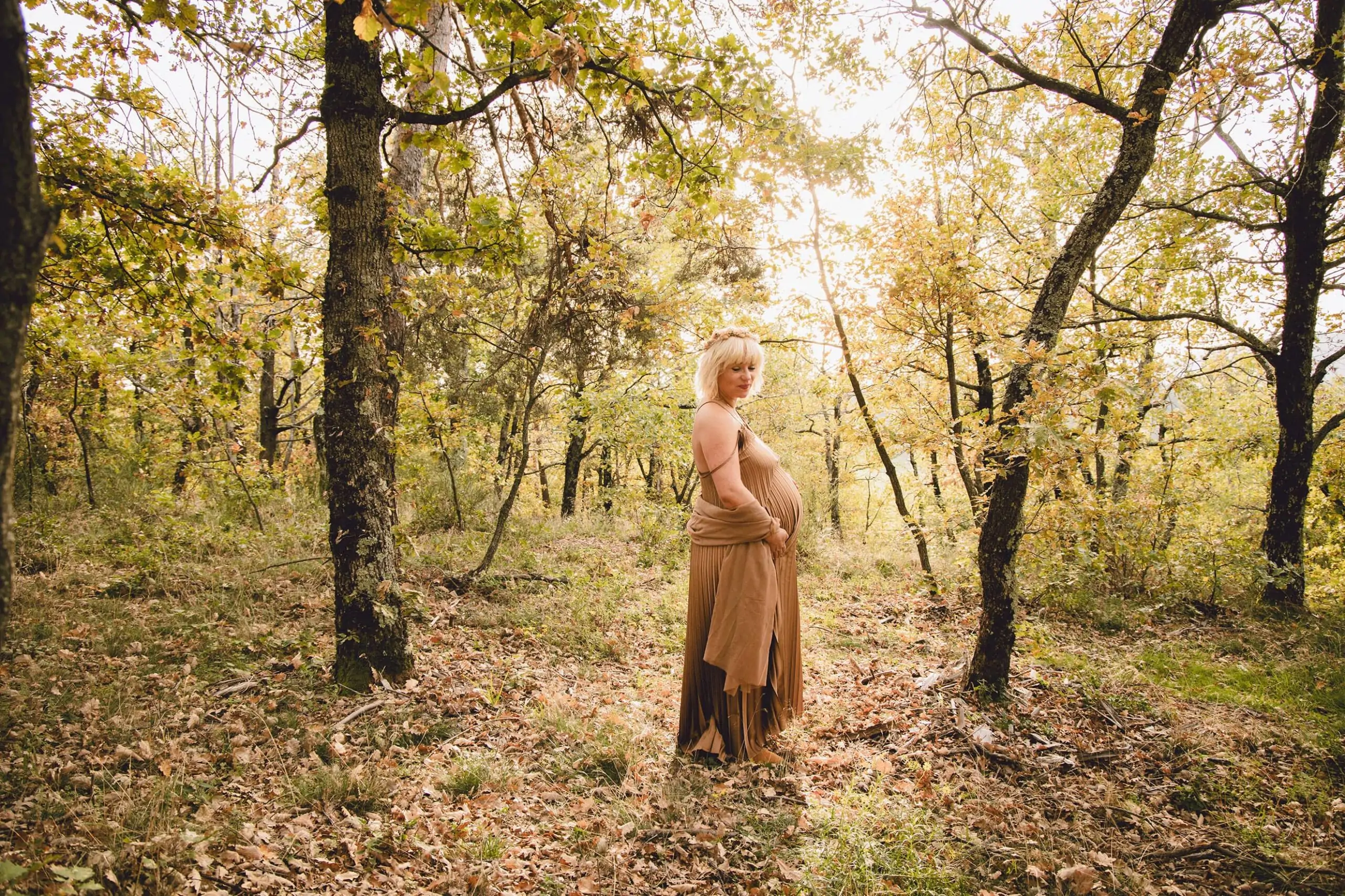 future maman en pleine nature à l'automne avec une couronne de fleurs