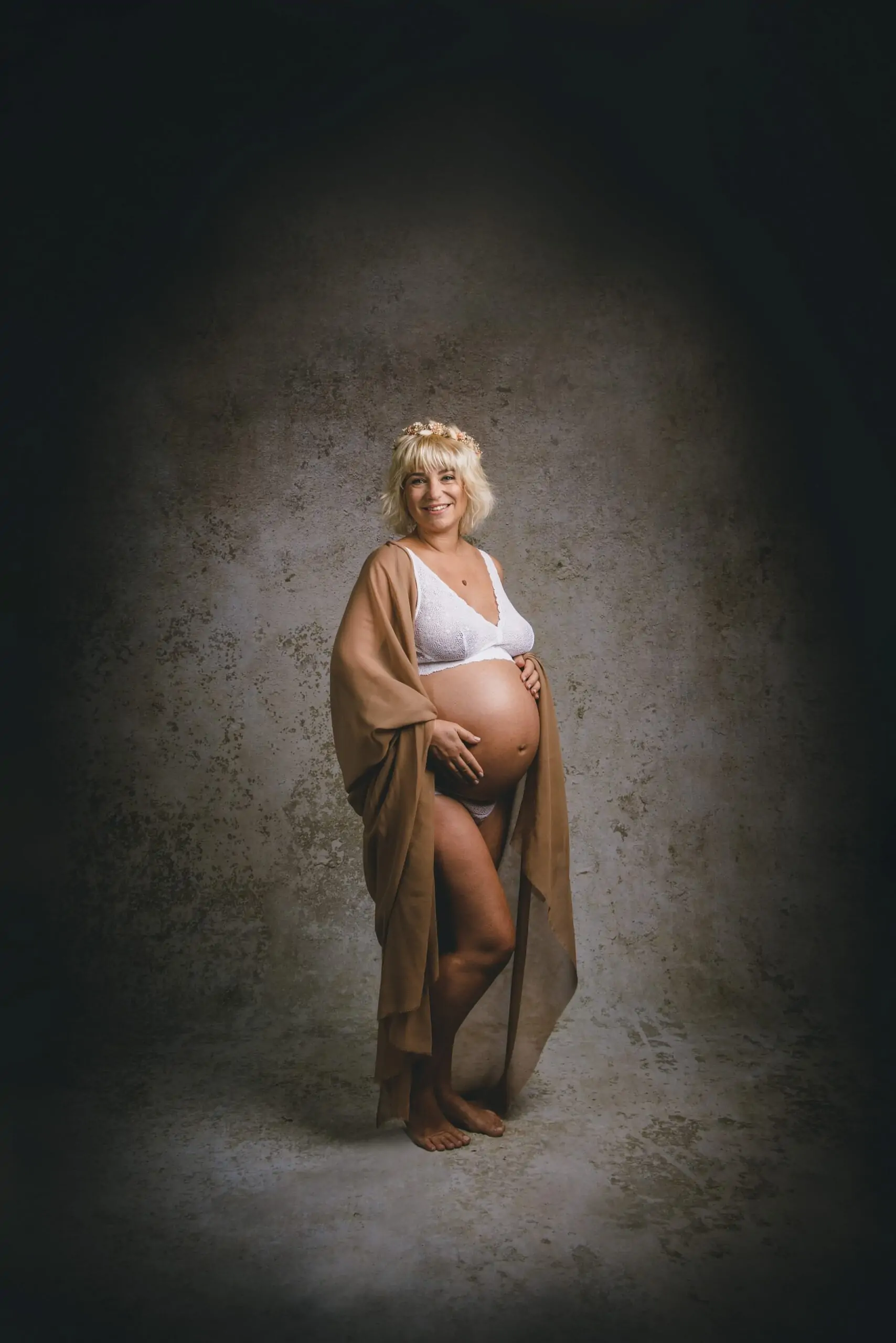 femme enceinte en studio photo avec une literie blanche et une étoile beige