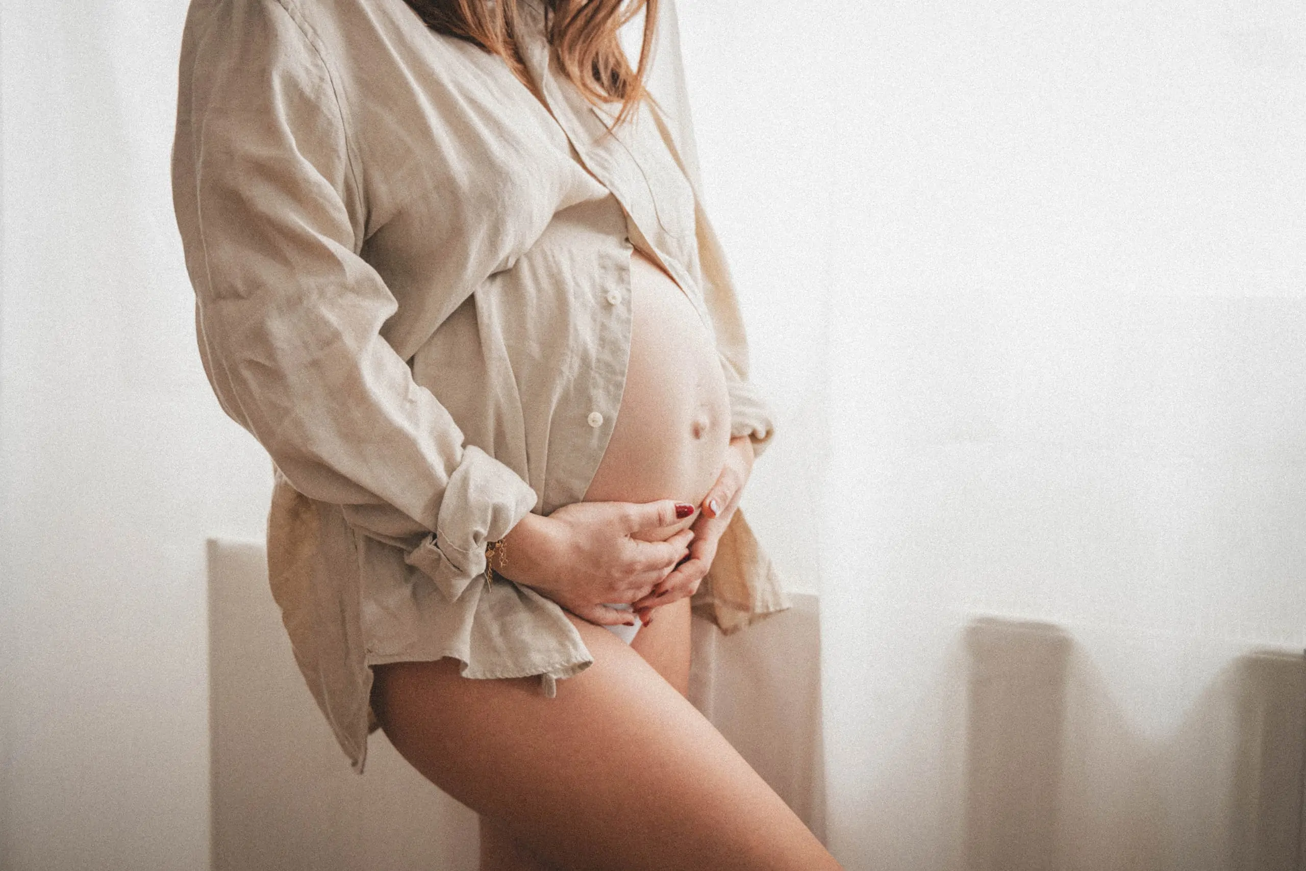 ventre d'une maman enceinte devant une fenêtre